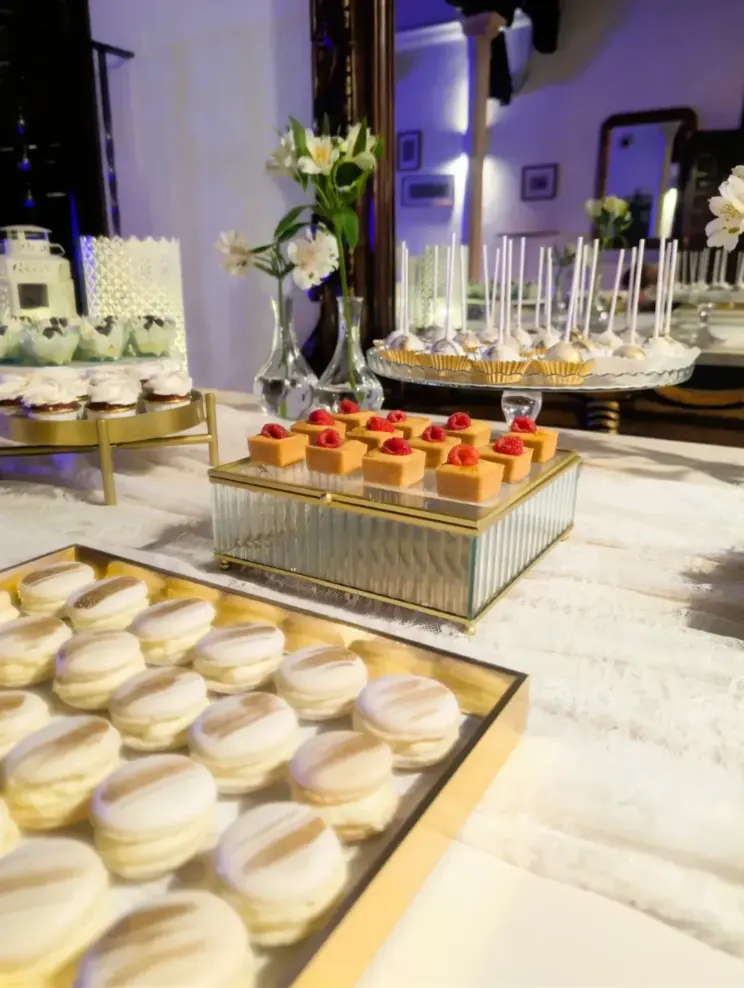 Mesa dulce de boda con macarons, minipostres de frambuesa, cake pops y repostería fina en bandejas doradas, elaborada por Magda Sweet Cakes en Granada.