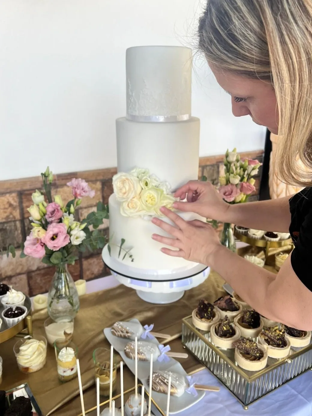 Magda of Magda Sweet Cakes arranging fresh flowers on a wedding cake in her Granada atelier.